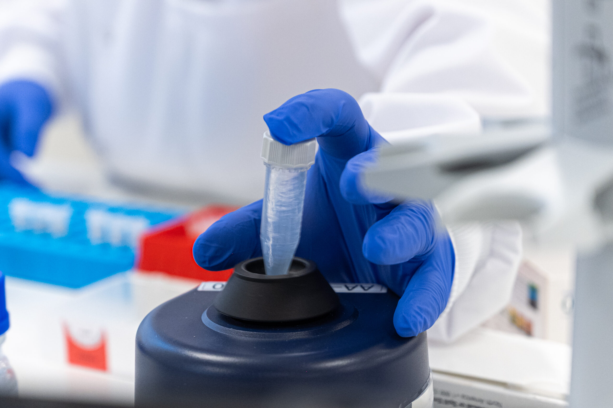 Gloved hand handling laboratory equipment.